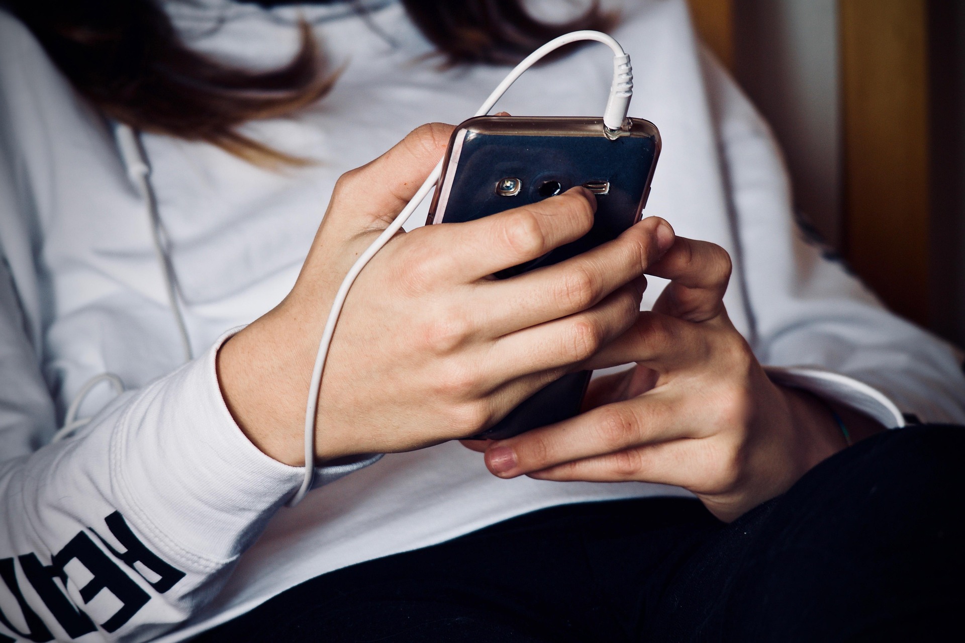 A woman looking at a phone with headphones attached | Source: Pixabay