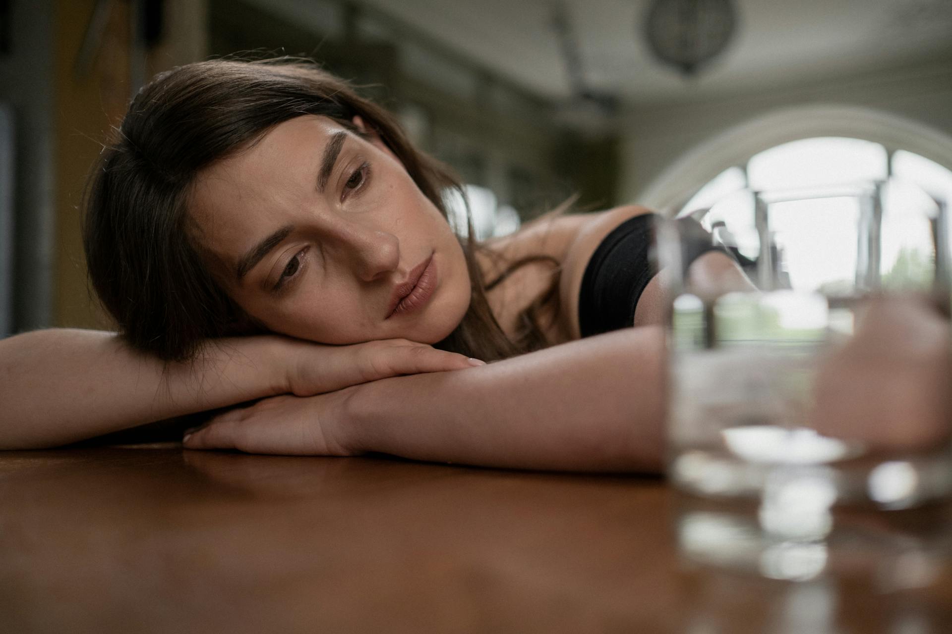 A worried woman with her head on a table | Source: Pexels