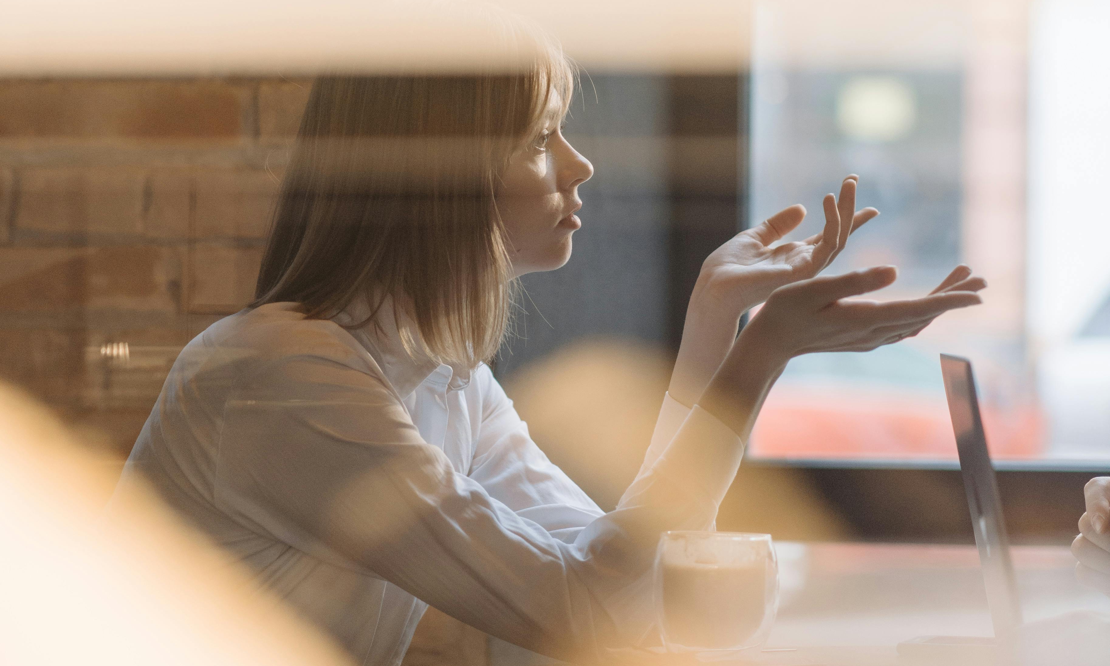 A woman in a cafe demonstrating with her hands | Source: Pexels